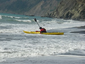 Yellow sea kayak launching into the surf during an intermediate kayak class